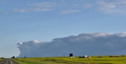 canola field with oil lease in distance storm cloud approaching