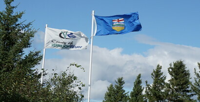 County of Vermilion River Flag and Province of AB flag above spruce trees